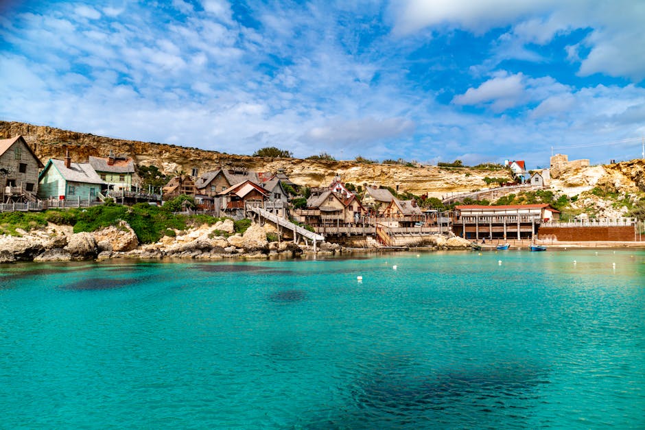 Charming view of a coastal village in Malta with azure waters and vibrant architecture.