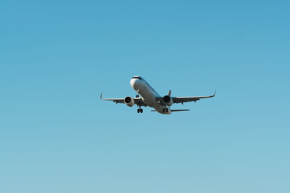 A commercial airplane flying during the day under a clear blue sky.