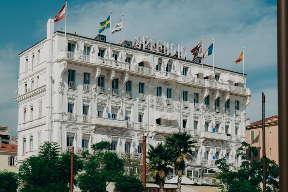 Elegant facade of Hotel Splendid in Cannes with vibrant flags under a sunny sky.