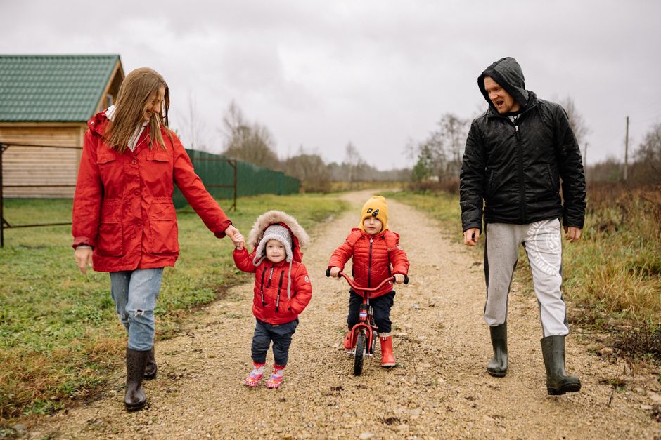 A family enjoys a cozy autumn walk with children in red coats and boots, enhancing togetherness.