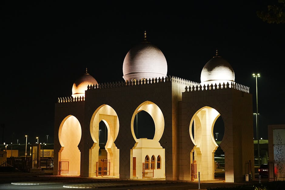 Illuminated domed structure in Abu Dhabi captured at night, showcasing intricate architectural details.
